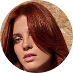 Close-up of a person with red hair, wearing a black top.